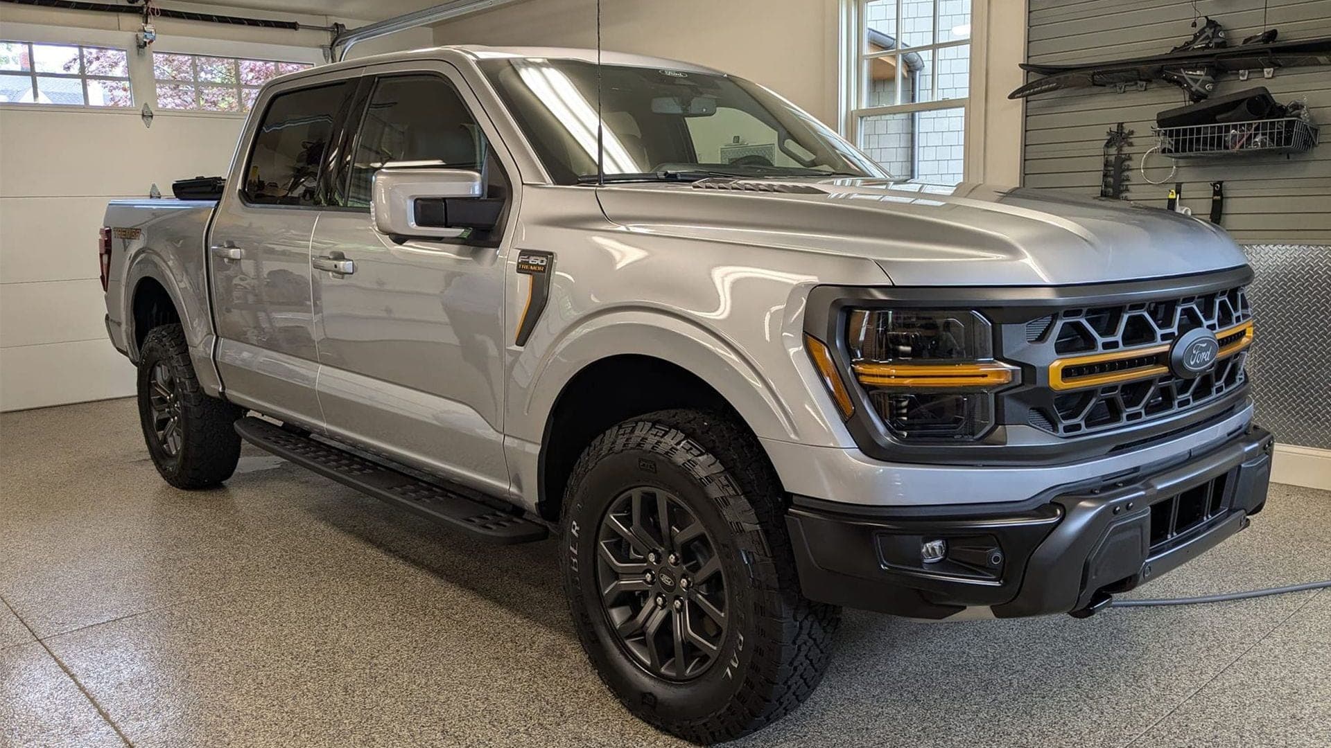 Silver Ford F-150 pickup truck parked in a garage with a speckled floor