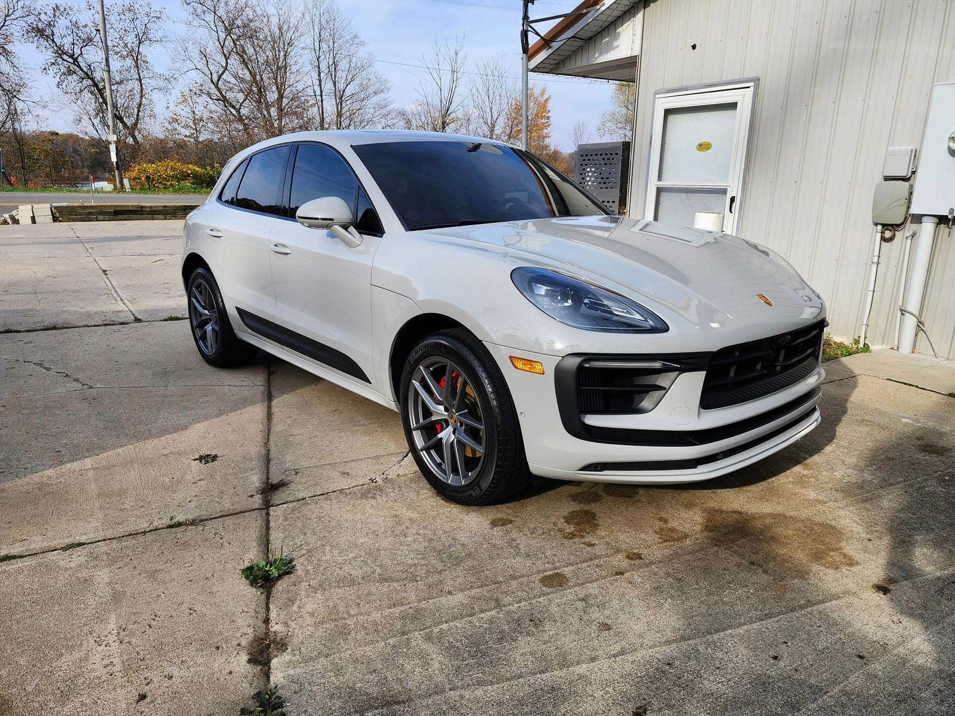 White Porsche Macan SUV parked on a concrete lot next to a white building