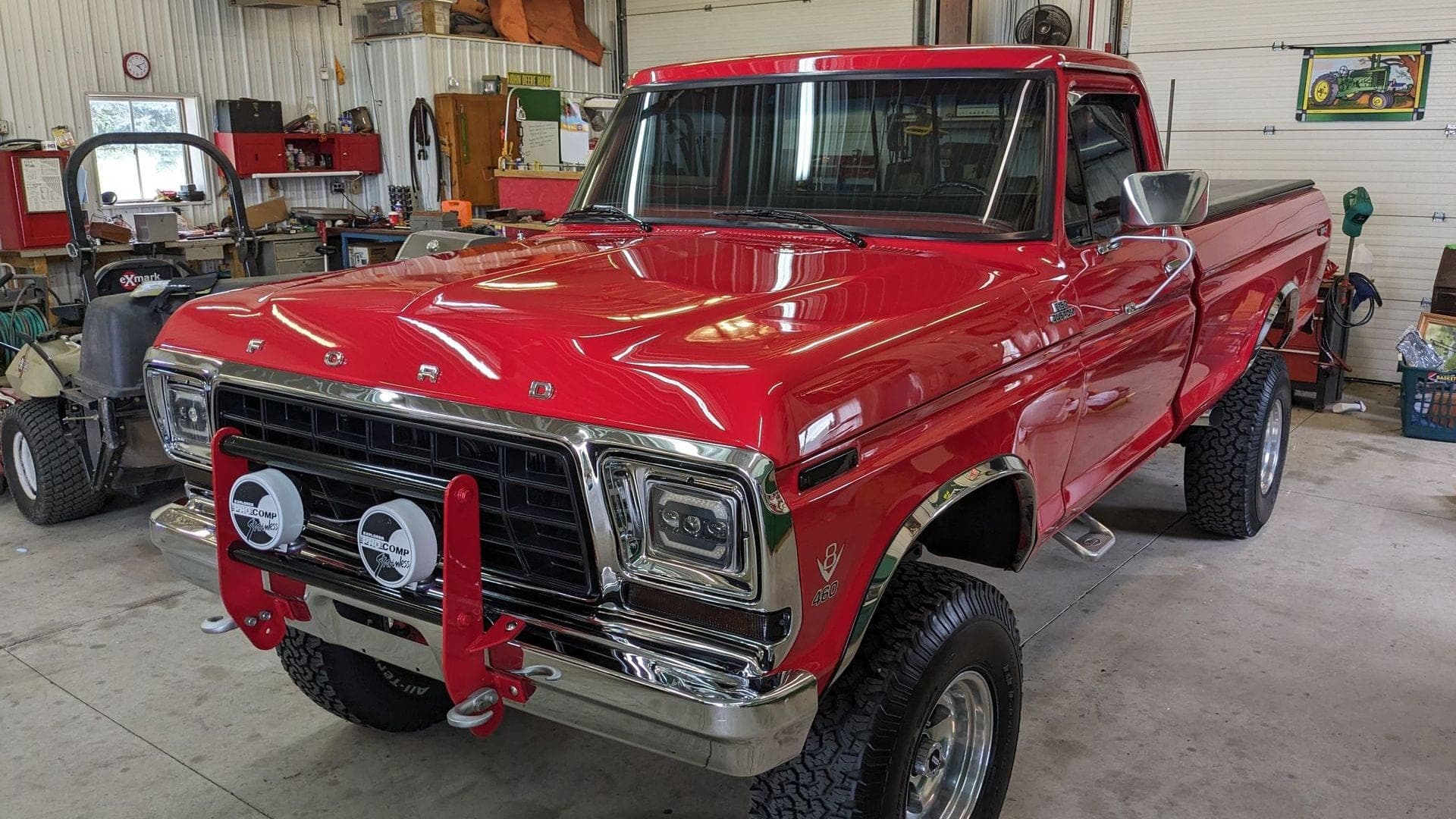 Red classic pickup truck with a chrome grille and lifted tires parked in a garage