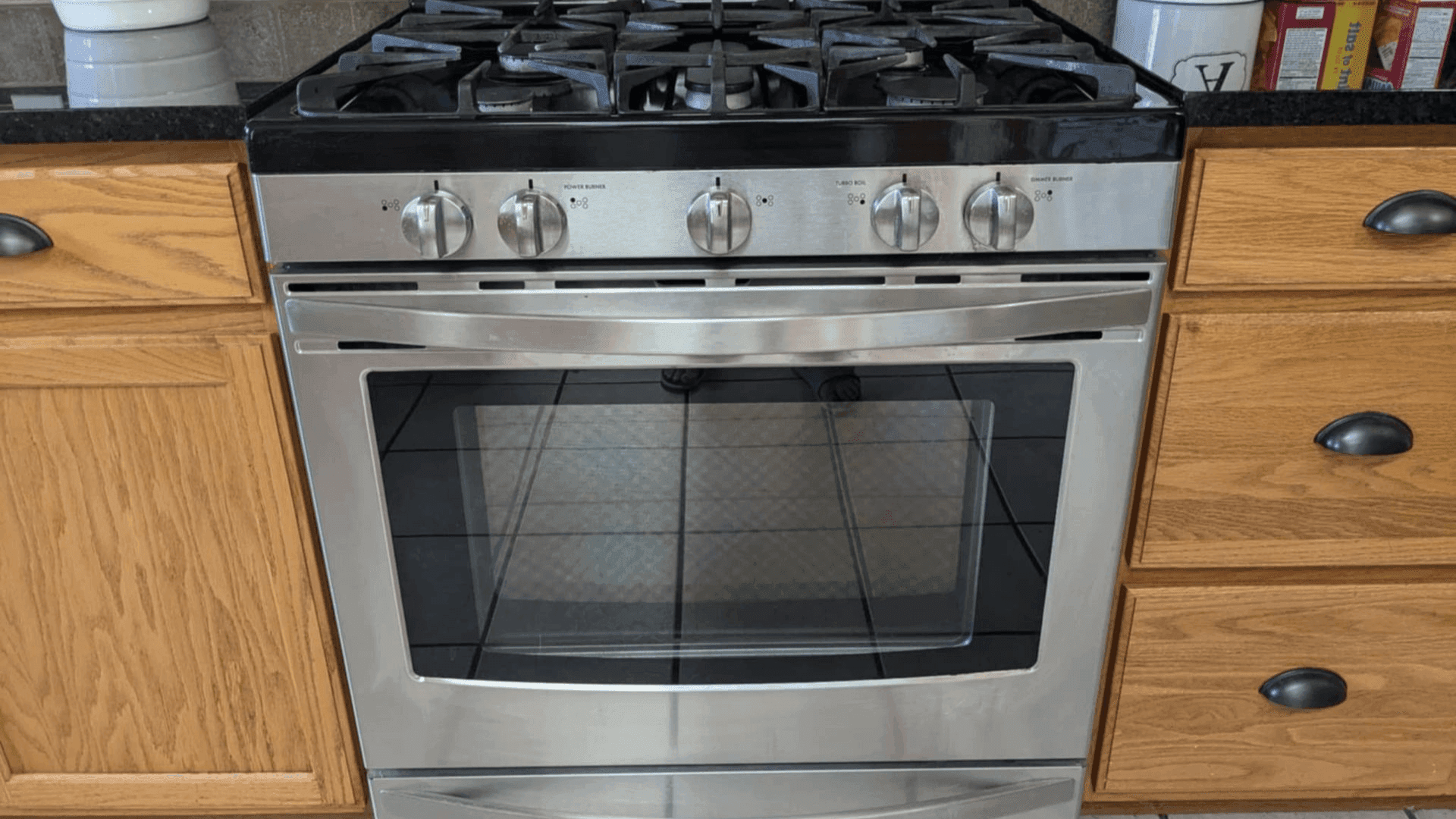 Stainless steel gas range between wooden kitchen cabinets